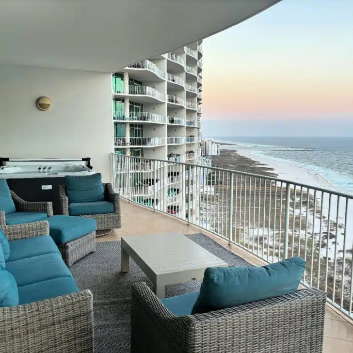 Private Gulf-front balcony with comfortable outdoor seating and a hot tub at Turquoise Place for Thanksgiving in Orange Beach overlooking the beach at sunset.